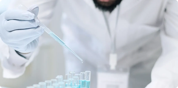 Scientist using a pipette to transfer liquid into test tubes during pharmaceutical and biopharmaceutical laboratory research.