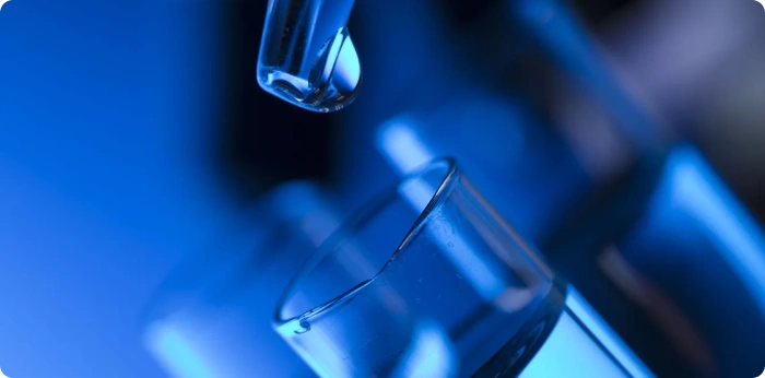 Close-up of a laboratory pipette transferring liquid into a test tube during pharmaceutical research and development