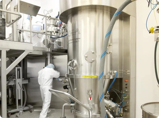 Pharmaceutical technician operating advanced API manufacturing equipment in a GMP-compliant production facility