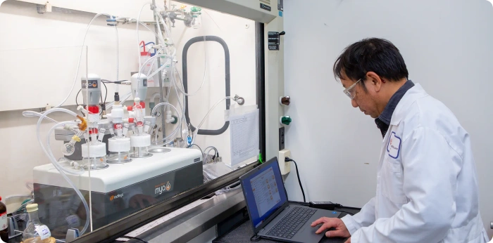 Scientist monitoring a bioreactor system for biologics process development in a CDMO laboratory
