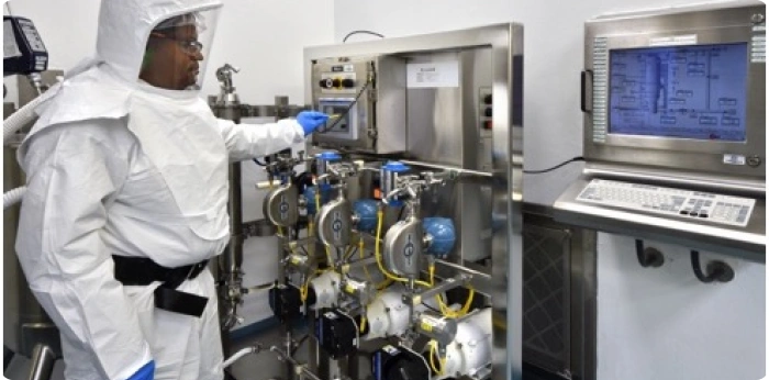 Pharmaceutical technician operating API manufacturing equipment in a controlled cleanroom facility
