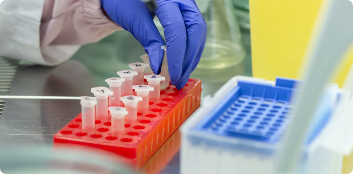 Scientist handling laboratory sample tubes for biologics research and testing