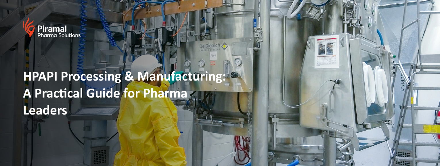 Technician operating HPAPI pharmaceutical manufacturing equipment in a controlled processing facility