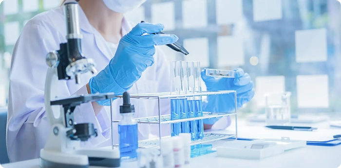 Scientist using microscope and test tubes for drug formulation and pharmaceutical research in laboratory