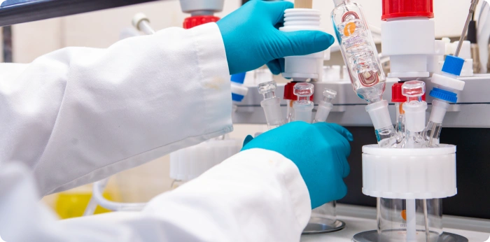 Lab technician adjusting glass bioreactor vessels and connectors during early-stage bioprocess development