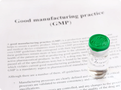 GMP compliance document with pharmaceutical vial representing quality assurance and regulatory standards in drug manufacturing