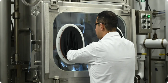 Technician using glovebox for HPAPI manufacturing