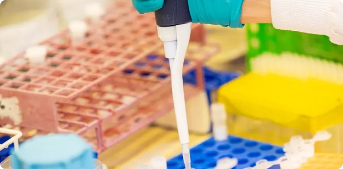 Scientist using micropipette for sample handling in pharmaceutical laboratory experiment