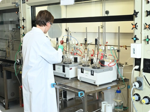 Research scientist operating chemical reactors and synthesis equipment in pharmaceutical laboratory