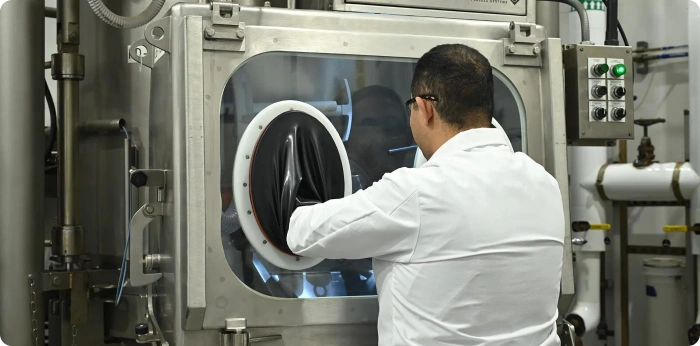 Scientist operating a containment isolator during high potency API manufacturing process