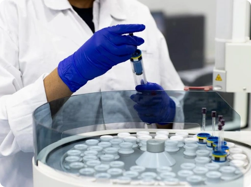 Scientist processing pharmaceutical sample vials using an automated laboratory system for quality control and analytical testing