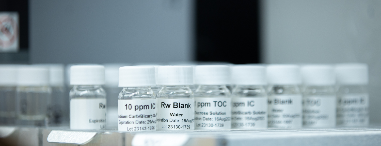 Row of labeled glass vials containing 10 ppm IC, Rw Blank, and ppm TOC calibration standards inside a laboratory