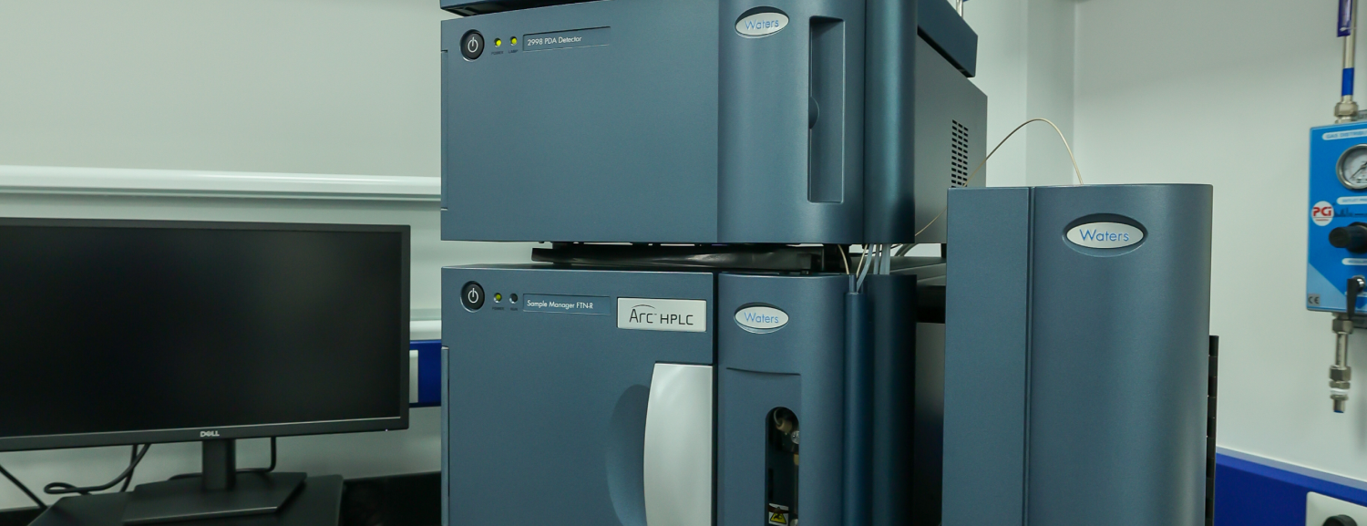 A close-up view of a dark grey, stacked modular HPLC or UPLC laboratory machine