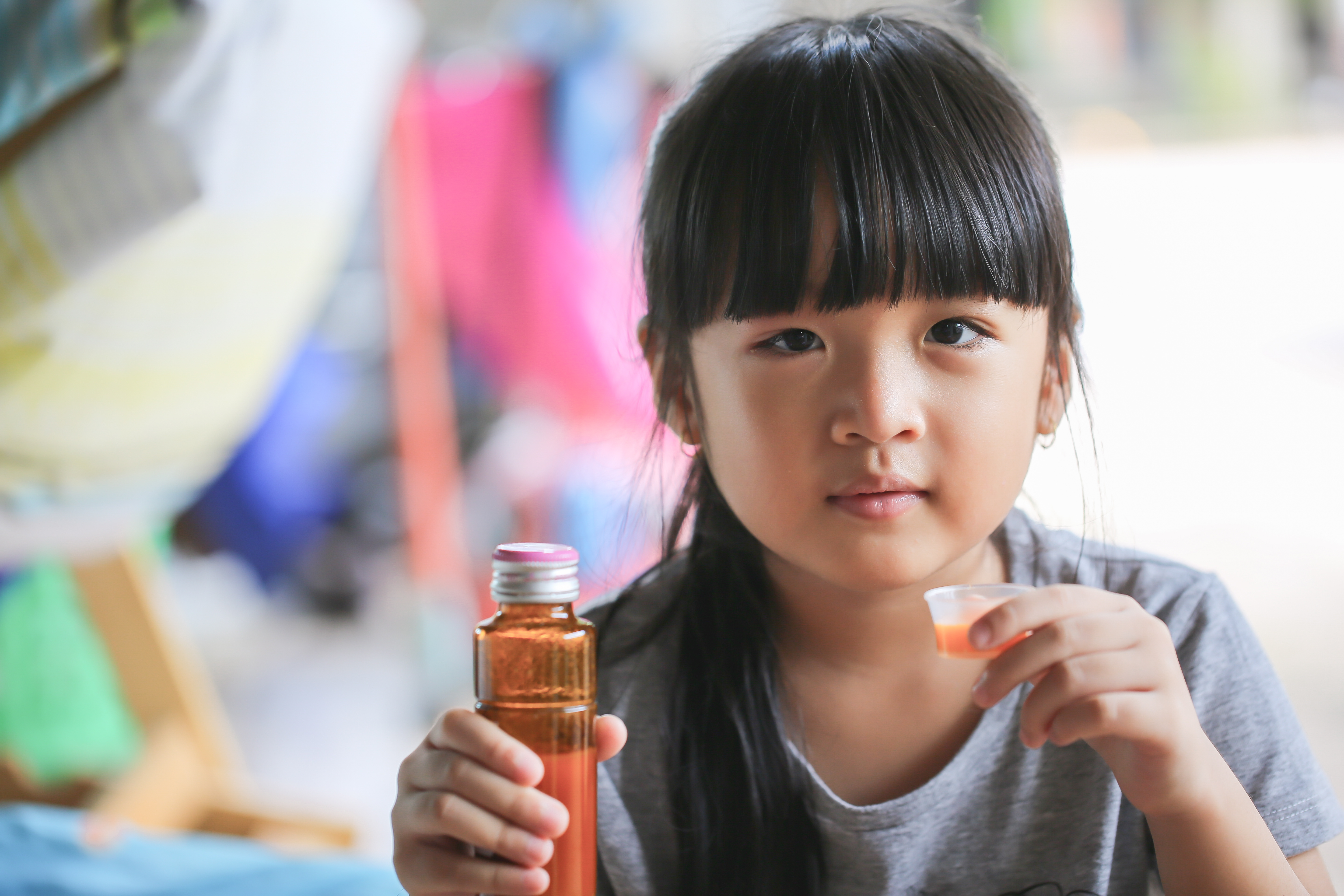 Asian kid takes medicine syrup by herself